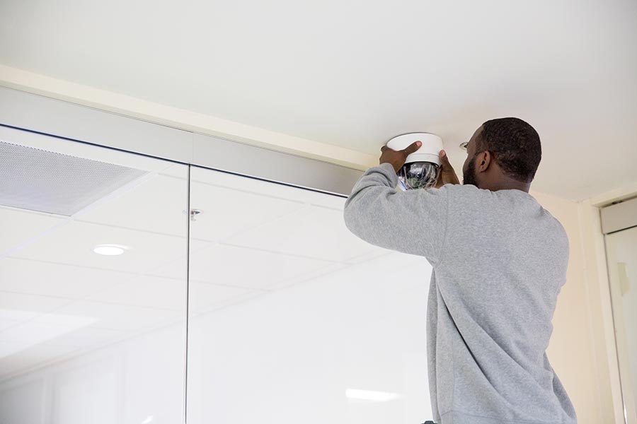 Technician installing a ceiling-mounted dome security camera