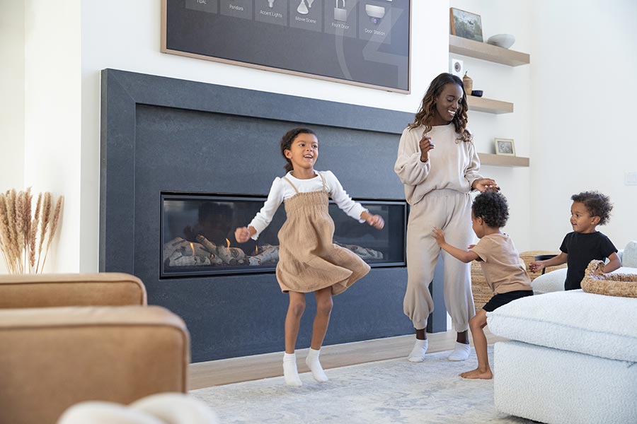 Woman and children playing in smart living room with fireplace and control panel above